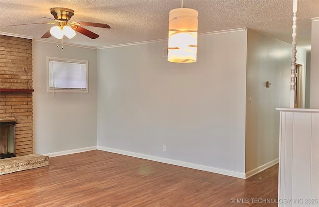 unfurnished living room featuring a ceiling fan, ornamental molding, a textured ceiling, and wood finished floors