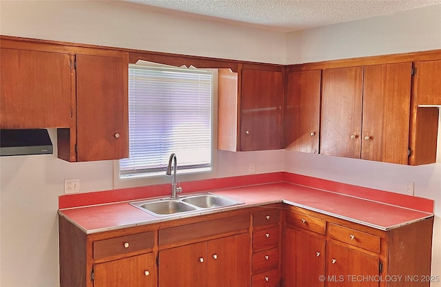 kitchen featuring a sink, brown cabinetry, a textured ceiling, and light countertops