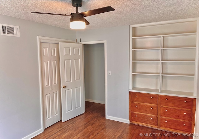 unfurnished bedroom with a textured ceiling, visible vents, wood finished floors, and baseboards