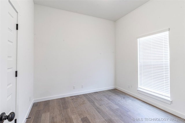 spare room featuring baseboards, a healthy amount of sunlight, and wood finished floors
