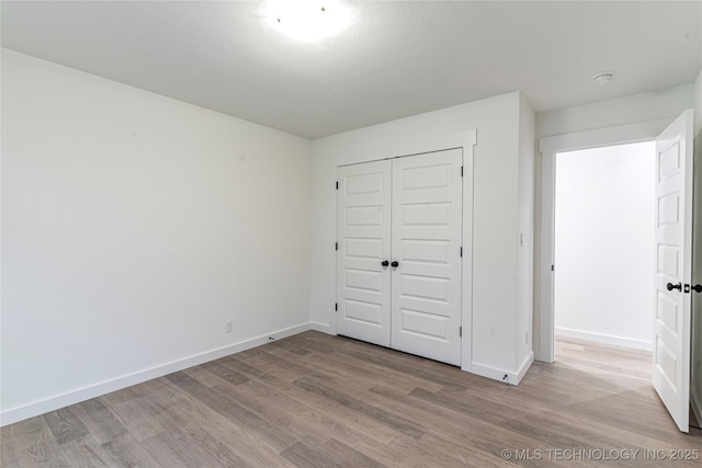 unfurnished bedroom featuring a closet, baseboards, and wood finished floors