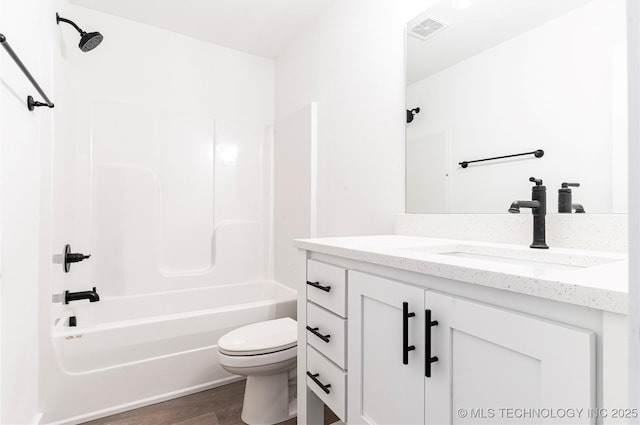 bathroom with toilet, wood finished floors, vanity, visible vents, and  shower combination