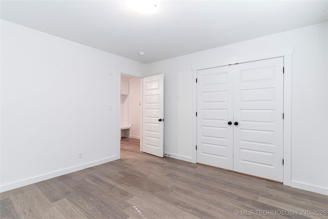 unfurnished bedroom featuring baseboards, a closet, and wood finished floors