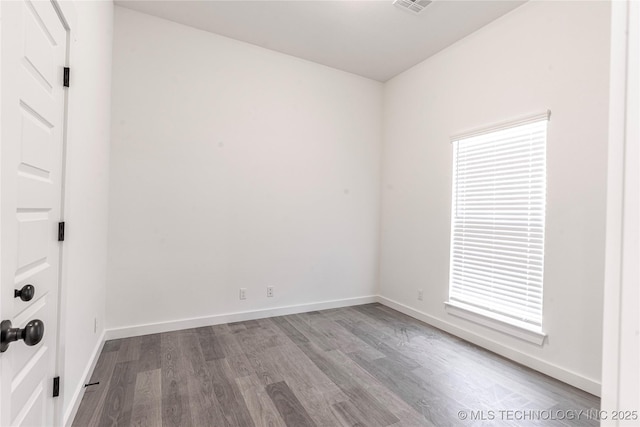 unfurnished room with baseboards, visible vents, and wood finished floors
