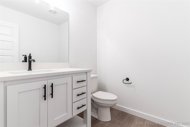 bathroom featuring toilet, wood finished floors, visible vents, baseboards, and vanity