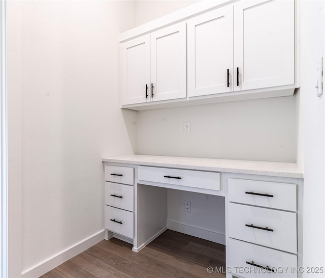 unfurnished office featuring built in study area, baseboards, and dark wood-style floors