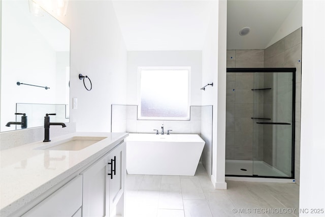 full bathroom featuring a stall shower, tile patterned floors, vanity, and a freestanding bath