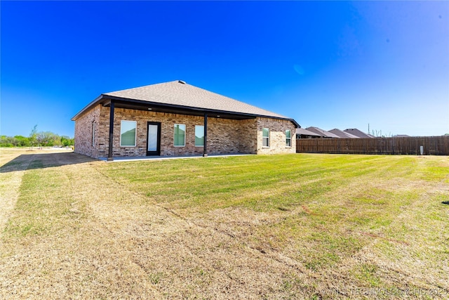 back of property with brick siding, fence, and a lawn