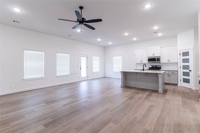 kitchen featuring a sink, visible vents, open floor plan, a ceiling fan, and appliances with stainless steel finishes