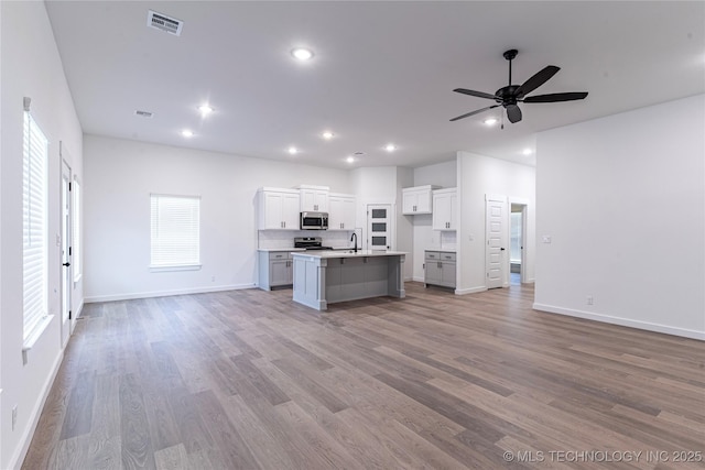 kitchen with light wood-type flooring, stainless steel appliances, baseboards, and open floor plan