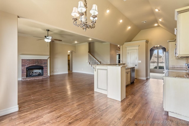 kitchen with dishwasher, ceiling fan with notable chandelier, open floor plan, arched walkways, and an island with sink