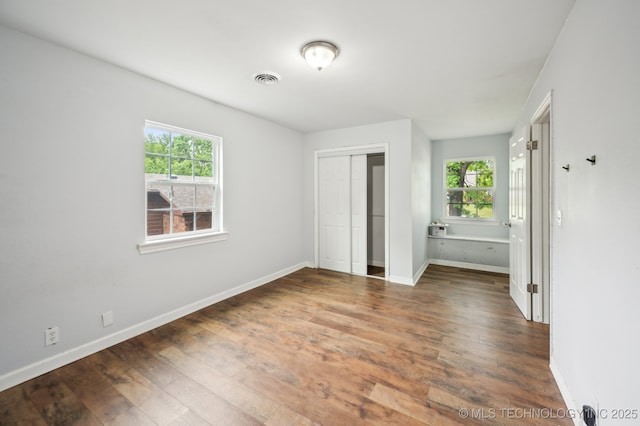 1109 S Division St, Sapulpa, OK 74066 - unfurnished bedroom with baseboards, multiple windows, a closet, and wood finished floors