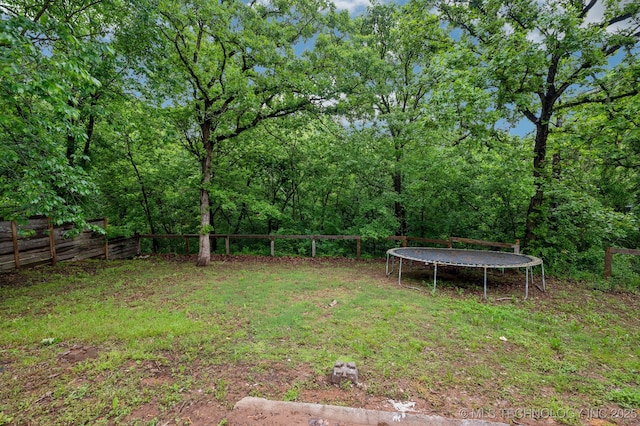 1109 S Division St, Sapulpa, OK 74066 - view of yard featuring a trampoline, fence, and a wooded view