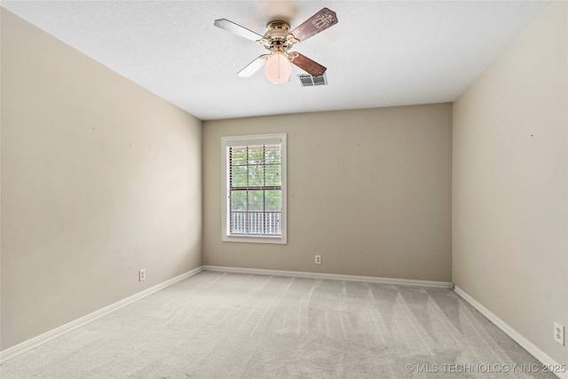 spare room with a ceiling fan, light carpet, and baseboards
