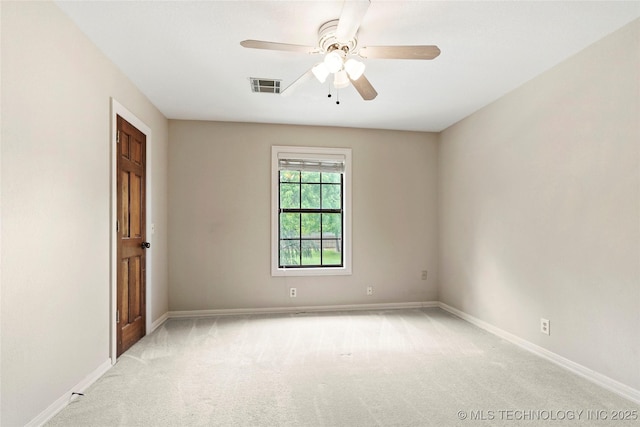 spare room featuring light colored carpet, baseboards, and ceiling fan