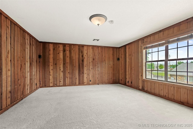 unfurnished room with wooden walls, carpet, and baseboards