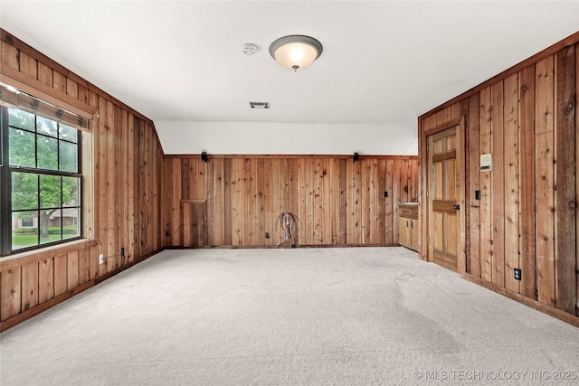 spare room featuring wood walls, light carpet, baseboards, and a smoke detector