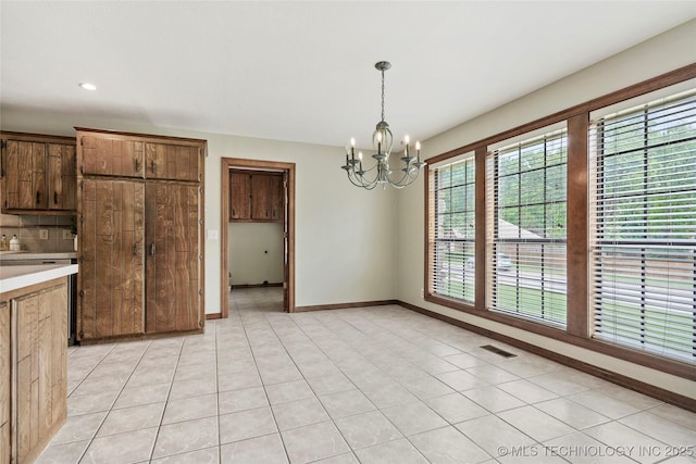 unfurnished dining area with a chandelier, baseboards, light tile patterned flooring, and recessed lighting