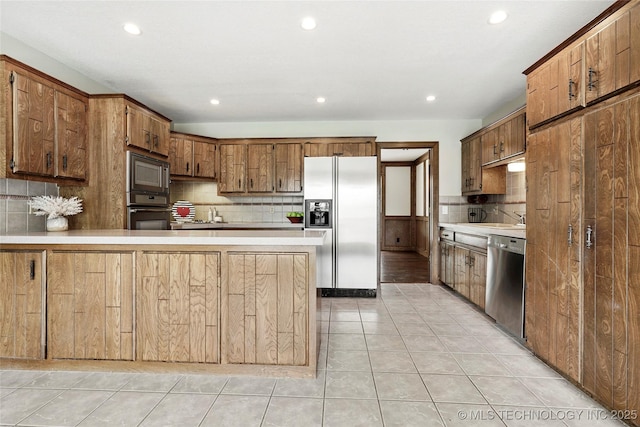 kitchen featuring appliances with stainless steel finishes, backsplash, light countertops, a peninsula, and recessed lighting