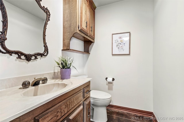 bathroom with toilet, vanity, and baseboards