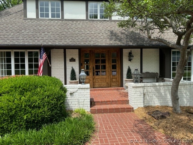 3421 E 62nd St, Tulsa, OK 74136 - view of exterior entry with roof with shingles, brick siding, and covered porch