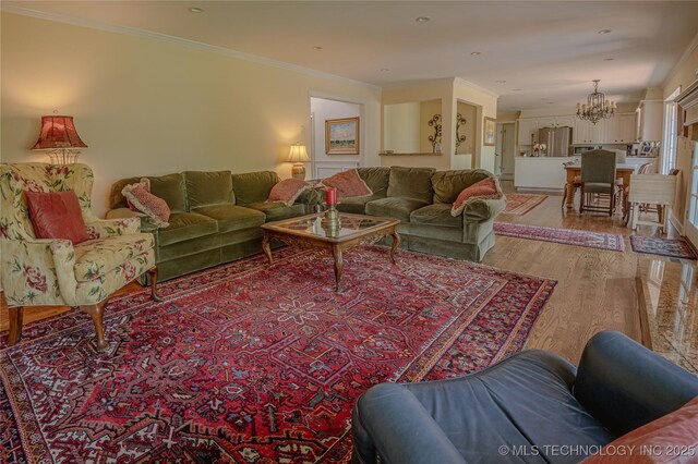 3421 E 62nd St, Tulsa, OK 74136 - living room featuring a chandelier, light wood-style flooring, and ornamental molding