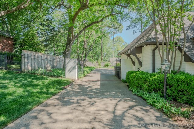 3421 E 62nd St, Tulsa, OK 74136 - view of side of property featuring driveway, a shingled roof, and brick siding