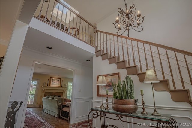 3421 E 62nd St, Tulsa, OK 74136 - staircase with crown molding, a chandelier, a towering ceiling, a decorative wall, and a fireplace