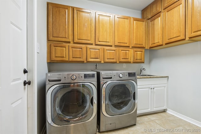 laundry room featuring light tile patterned floors, a sink, cabinet space, washing machine and clothes dryer, and baseboards