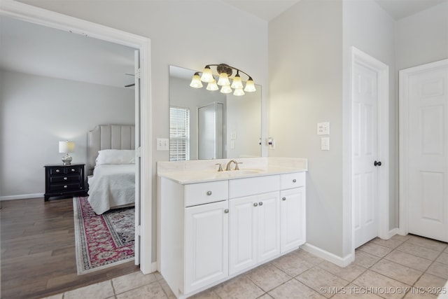 ensuite bathroom featuring tile patterned floors, ensuite bath, baseboards, and vanity