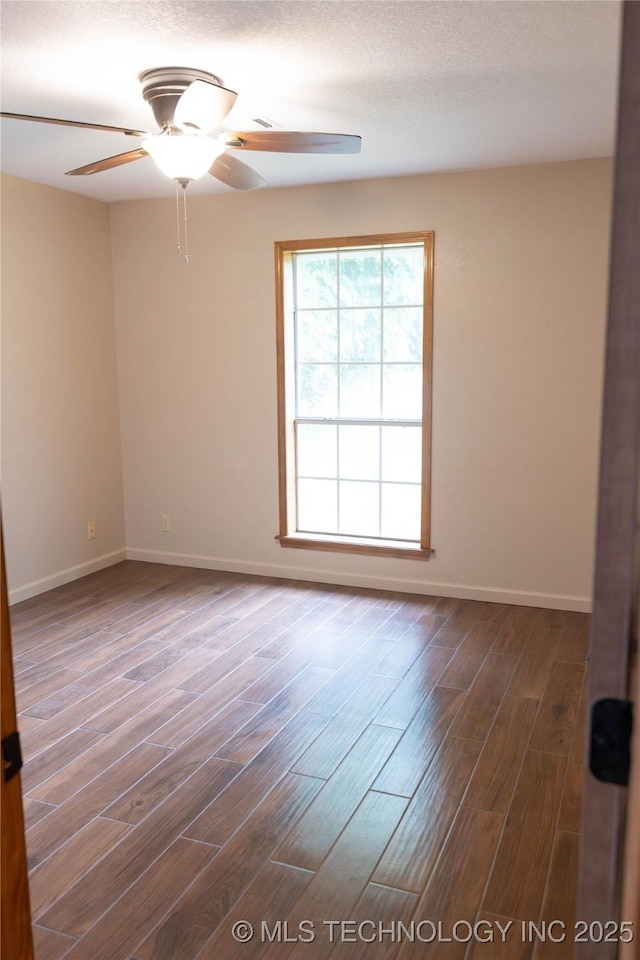 spare room featuring baseboards, wood finished floors, and a ceiling fan