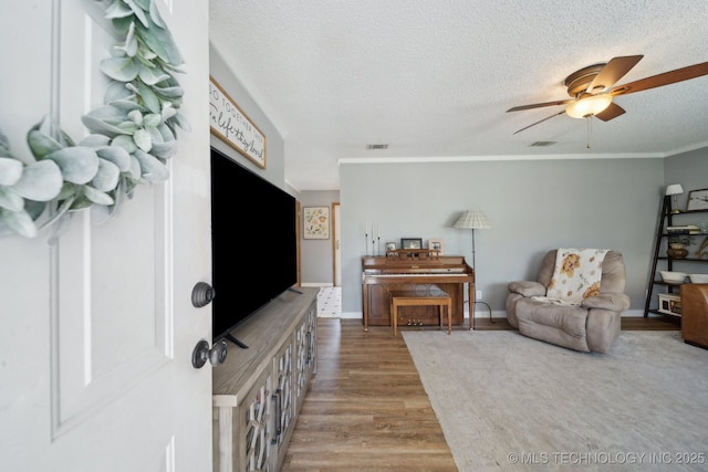 141 S Bryan St, Copan, OK 74022 - living room with a textured ceiling, visible vents, wood finished floors, and a ceiling fan