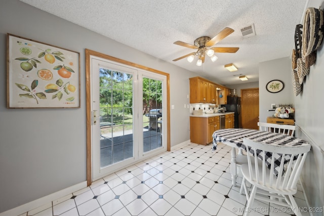 141 S Bryan St, Copan, OK 74022 - kitchen with freestanding refrigerator, light floors, brown cabinetry, visible vents, and ceiling fan