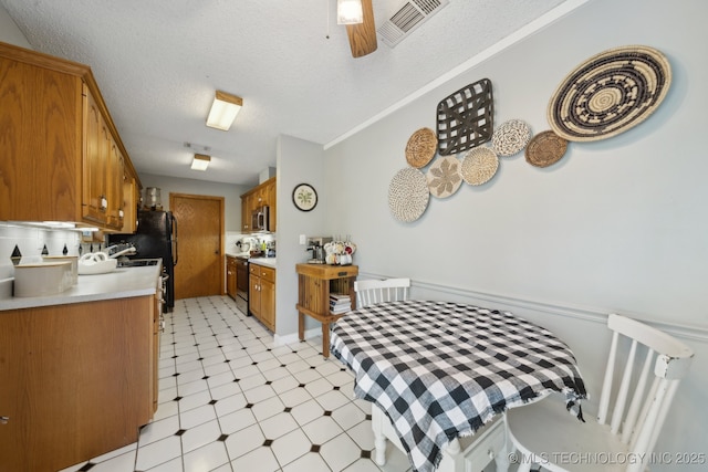 141 S Bryan St, Copan, OK 74022 - kitchen with brown cabinetry, light floors, visible vents, light countertops, and range with electric cooktop