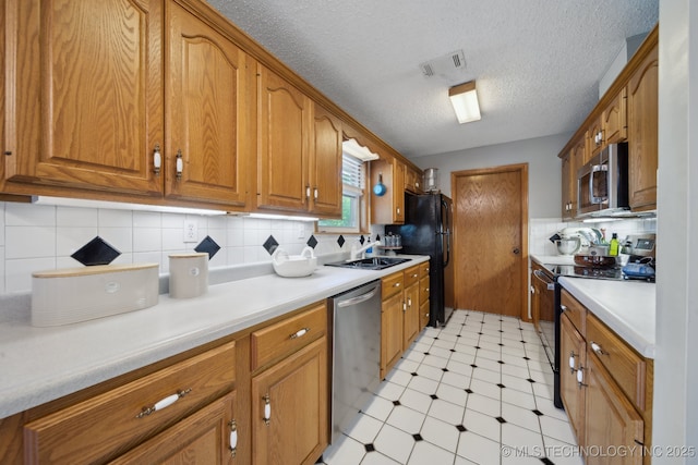 141 S Bryan St, Copan, OK 74022 - kitchen with appliances with stainless steel finishes, visible vents, light floors, and brown cabinetry