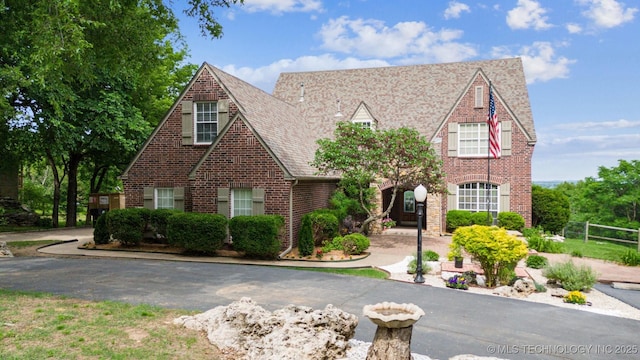 tudor-style house with brick siding and fence