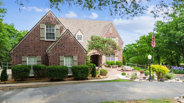 english style home with an outdoor fire pit, brick siding, and a patio area
