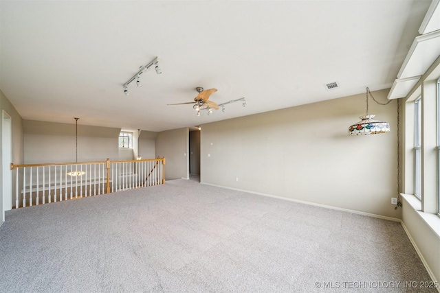 carpeted spare room with baseboards, visible vents, ceiling fan, and track lighting