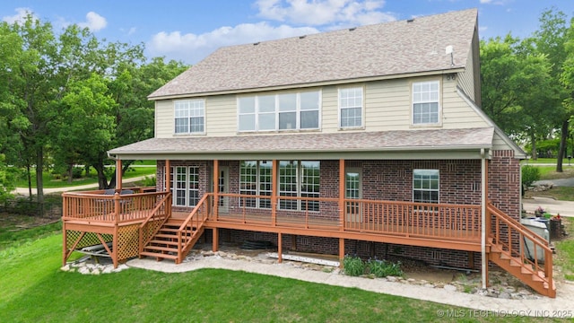 rear view of house with stairway, a deck, a shingled roof, and a yard