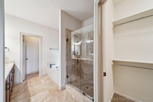 bathroom featuring a stall shower, vanity, a garden tub, and baseboards