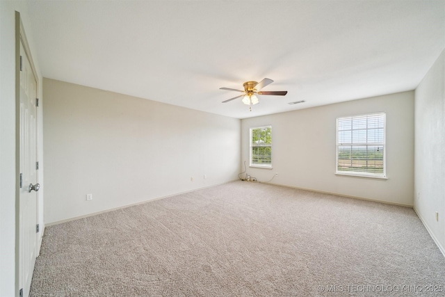 spare room with a ceiling fan, baseboards, visible vents, and light colored carpet