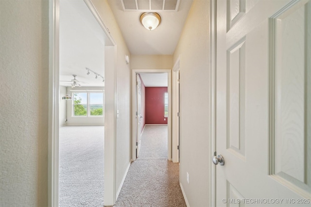 hallway featuring carpet flooring, baseboards, and visible vents