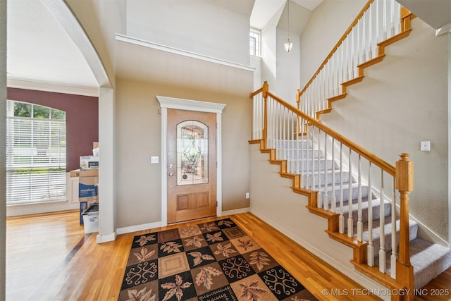 foyer entrance featuring stairs, baseboards, a towering ceiling, and wood finished floors