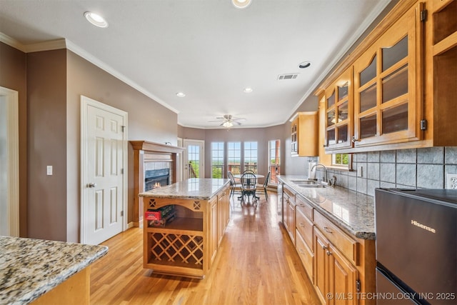 kitchen featuring open shelves, crown molding, light wood-style flooring, and light stone countertops
