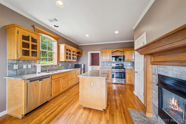 kitchen featuring a sink, stainless steel appliances, visible vents, crown molding, and a kitchen island