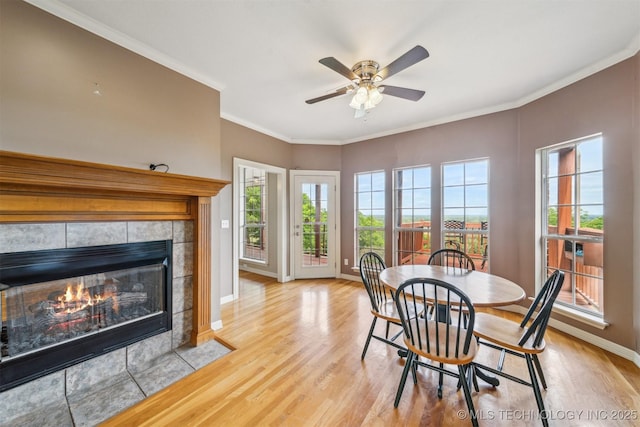 dining area with a wealth of natural light, wood finished floors, a fireplace, and ornamental molding