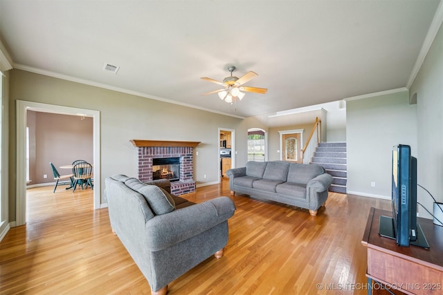 living area featuring light wood finished floors, crown molding, visible vents, stairway, and ceiling fan