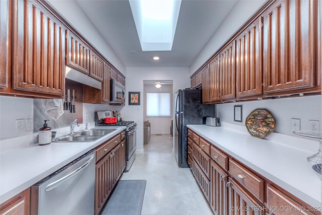 kitchen with light countertops, appliances with stainless steel finishes, a skylight, and a sink