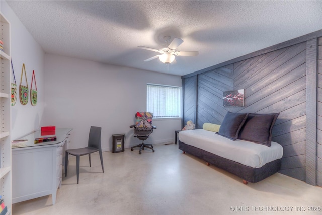 bedroom featuring a textured ceiling, wood walls, a ceiling fan, and concrete flooring