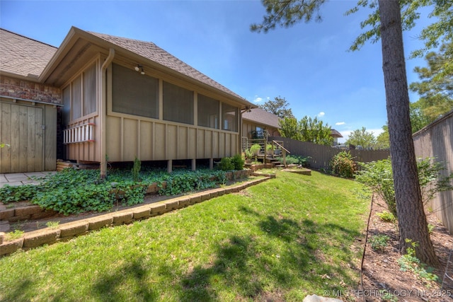 view of property exterior featuring a sunroom, fence, a lawn, a shingled roof, and board and batten siding